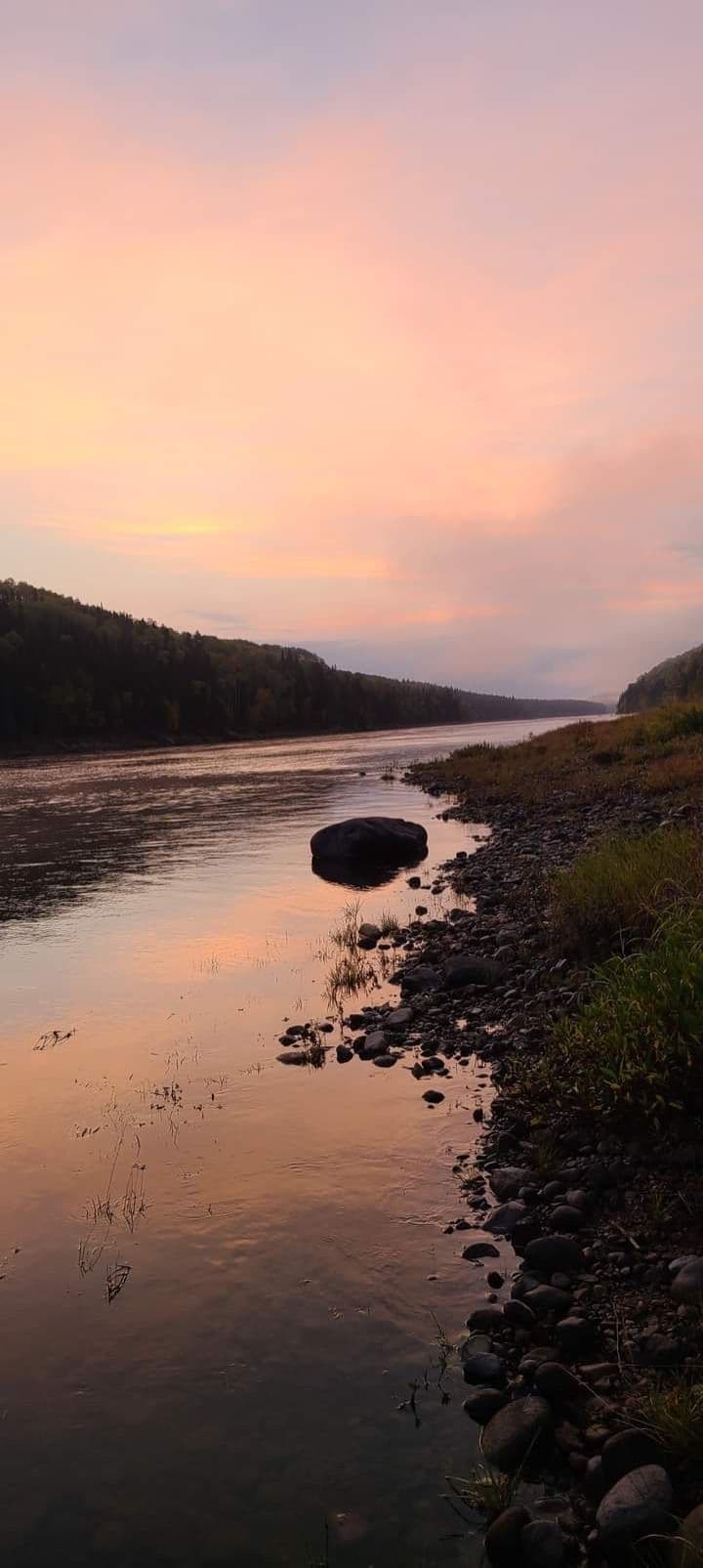 Boreal river at sunset, pastel pink sky, rocky shoreline